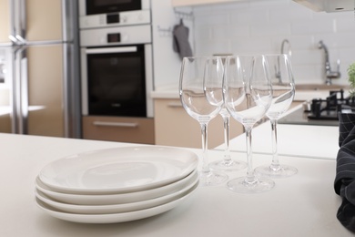 Photo of Stack of clean dishes and glasses on table in kitchen