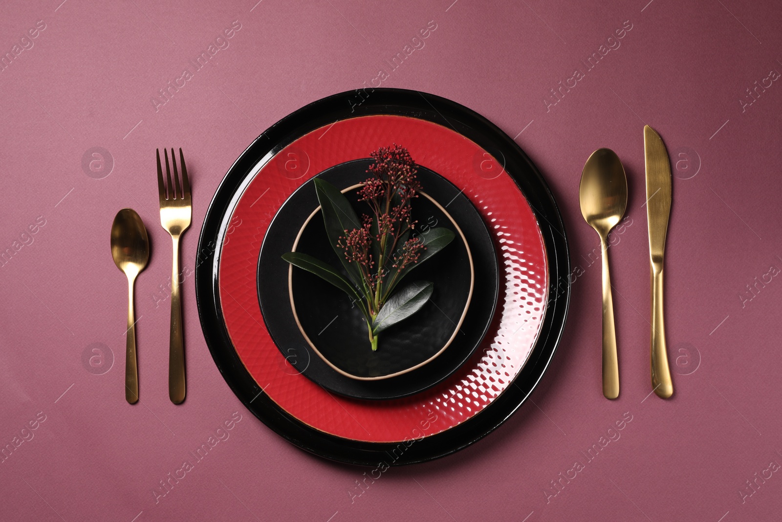 Photo of Stylish table setting with cutlery and floral decor on pink background, flat lay