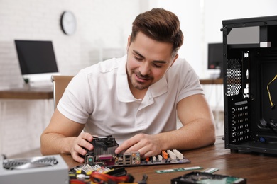 Male technician repairing motherboard at table indoors