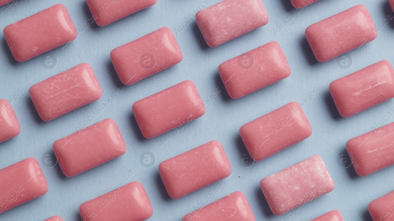 Photo of Many sweet chewing gums on light blue background, flat lay