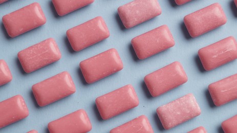 Photo of Many sweet chewing gums on light blue background, flat lay