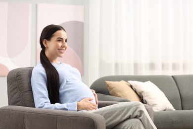 Photo of Happy pregnant woman on armchair at home