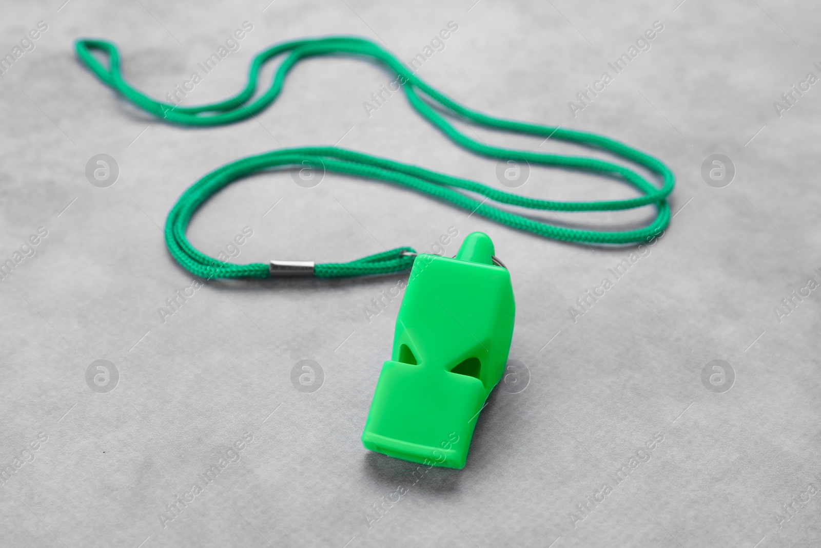 Photo of One green whistle with cord on light grey table