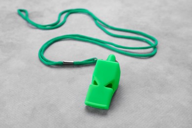 One green whistle with cord on light grey table