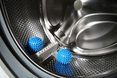 Blue dryer balls in washing machine drum, closeup