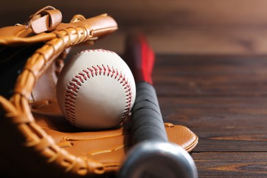 Photo of Baseball glove, bat and ball on wooden table, closeup. Space for text
