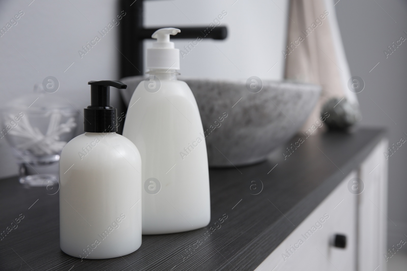 Photo of Dispensers of liquid soap on countertop in bathroom. Space for text