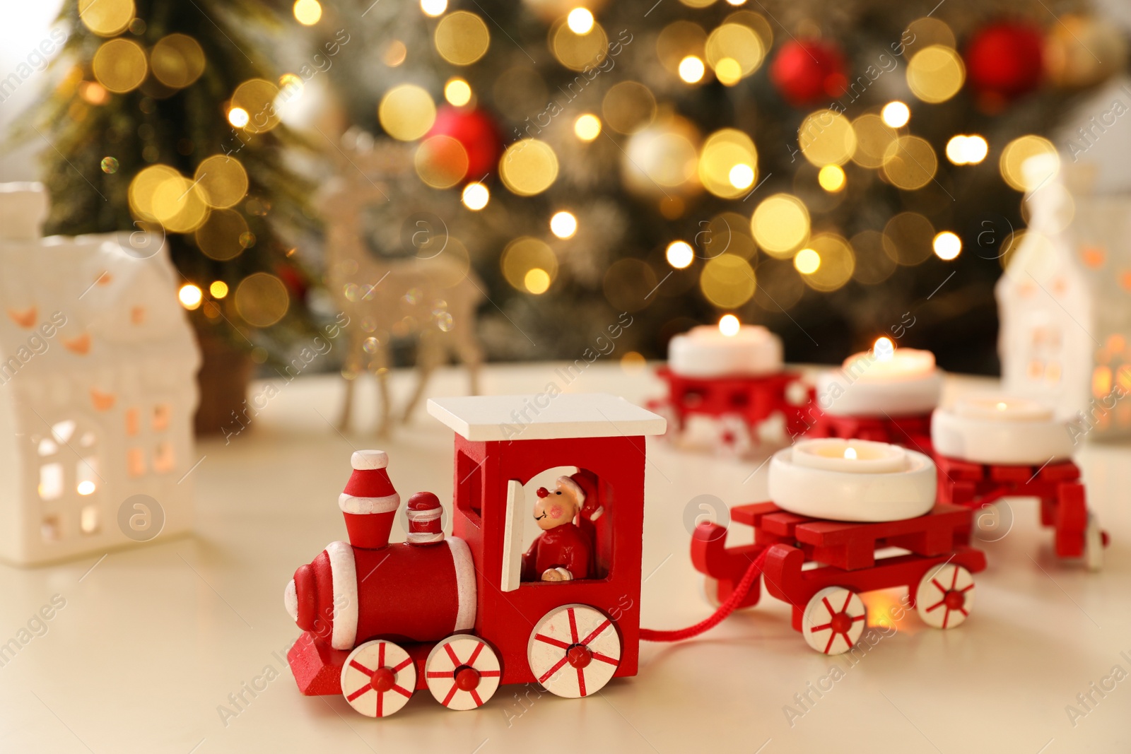 Photo of Red toy train as Christmas candle holder on white table in room