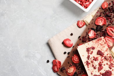 Photo of Different chocolate bars with freeze dried fruits on grey marble table, flat lay. Space for text