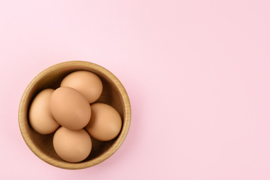 Photo of Raw chicken eggs on pink background, top view. Space for text