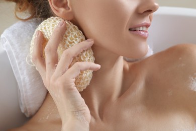 Photo of Woman rubbing her neck with sponge while taking bath, closeup