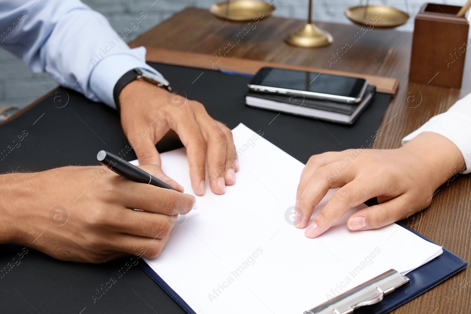 Photo of Male lawyer working with client at table in office