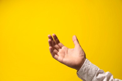 Photo of Man holding something in hand on yellow background, closeup. Space for text