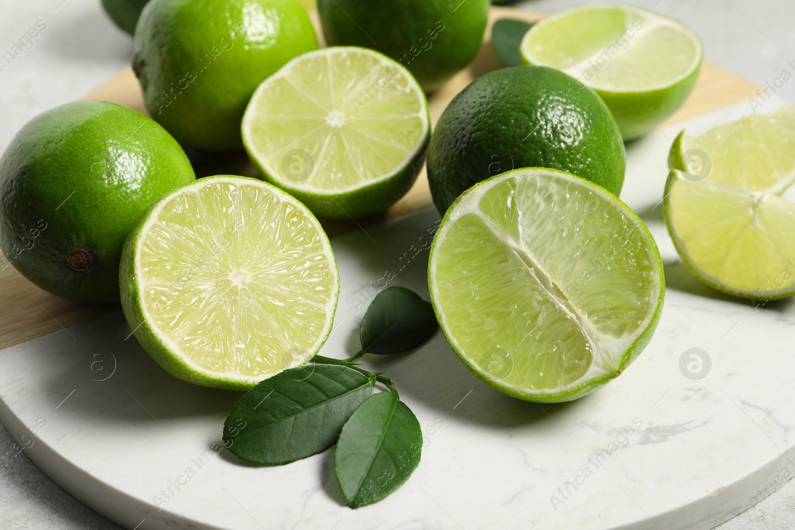 Photo of Fresh ripe limes and leaves on table, closeup