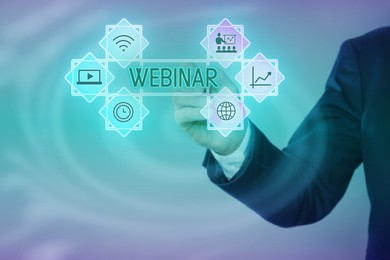 Webinar. Businessman using virtual screen with icons on color background, closeup