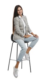 Beautiful young woman sitting on stool against white background