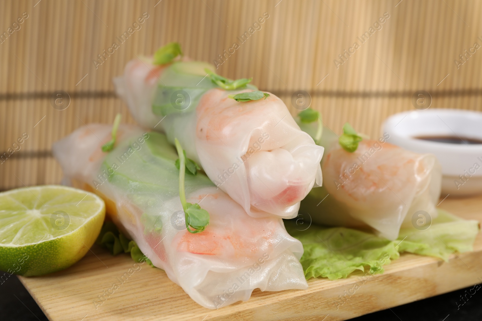 Photo of Delicious spring rolls, lime and lettuce on table, closeup