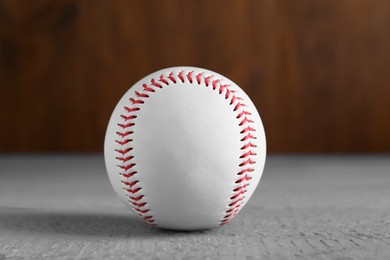 Photo of Baseball ball on grey wooden table, closeup. Sportive equipment