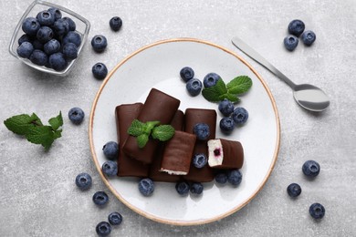 Photo of Delicious glazed curd snacks with fresh blueberries and mint on light grey table, flat lay