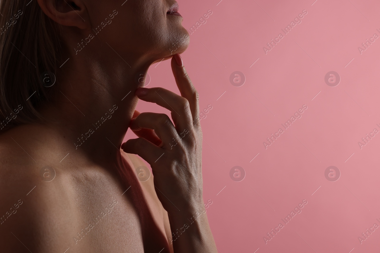 Photo of Woman touching her neck on pink background, closeup. Space for text