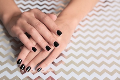 Photo of Woman showing black manicure on shining background, closeup with space for text. Nail polish trends