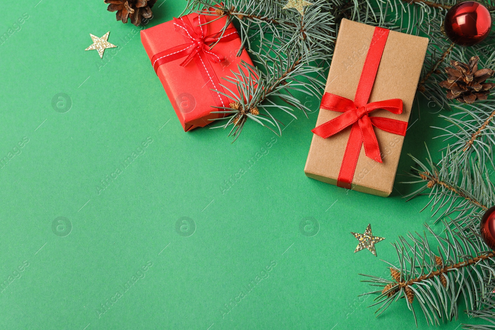 Photo of Flat lay composition with decorated fir branches and gifts on green background, space for text. Winter holidays