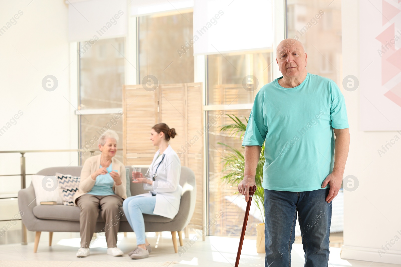 Photo of Elderly man with cane in nursing home, space for text. Assisting senior generation