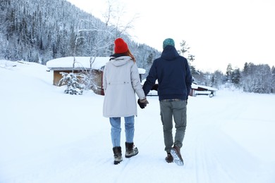 Photo of Couple walking on snowy day, back view. Winter vacation