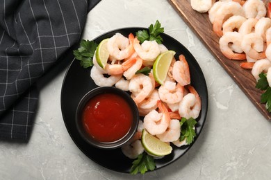 Tasty boiled shrimps with cocktail sauce, parsley and lime on light grey table, flat lay