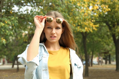 Photo of Young woman wearing stylish sunglasses in park