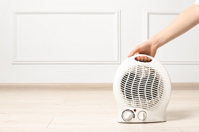 Photo of Young woman holding electric fan heater indoors, closeup. Space for text
