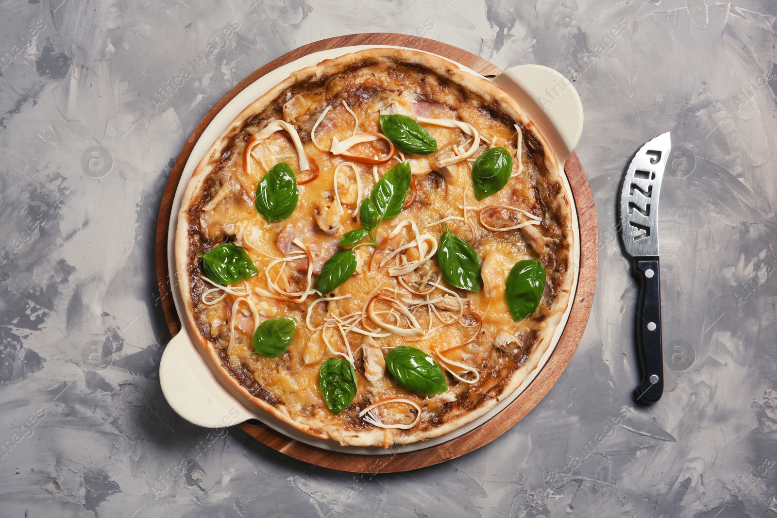 Photo of Board with delicious homemade pizza and knife on grunge background, top view