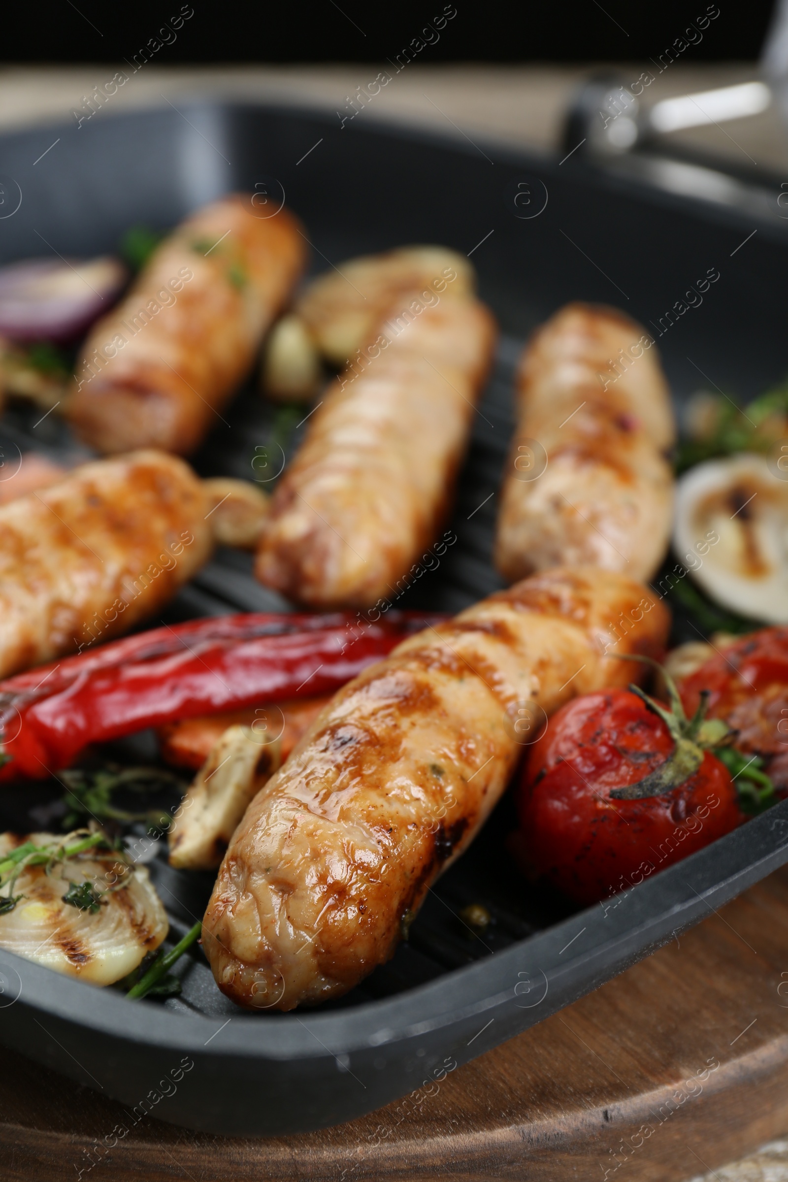 Photo of Tasty fresh grilled sausages with vegetables on wooden table, closeup