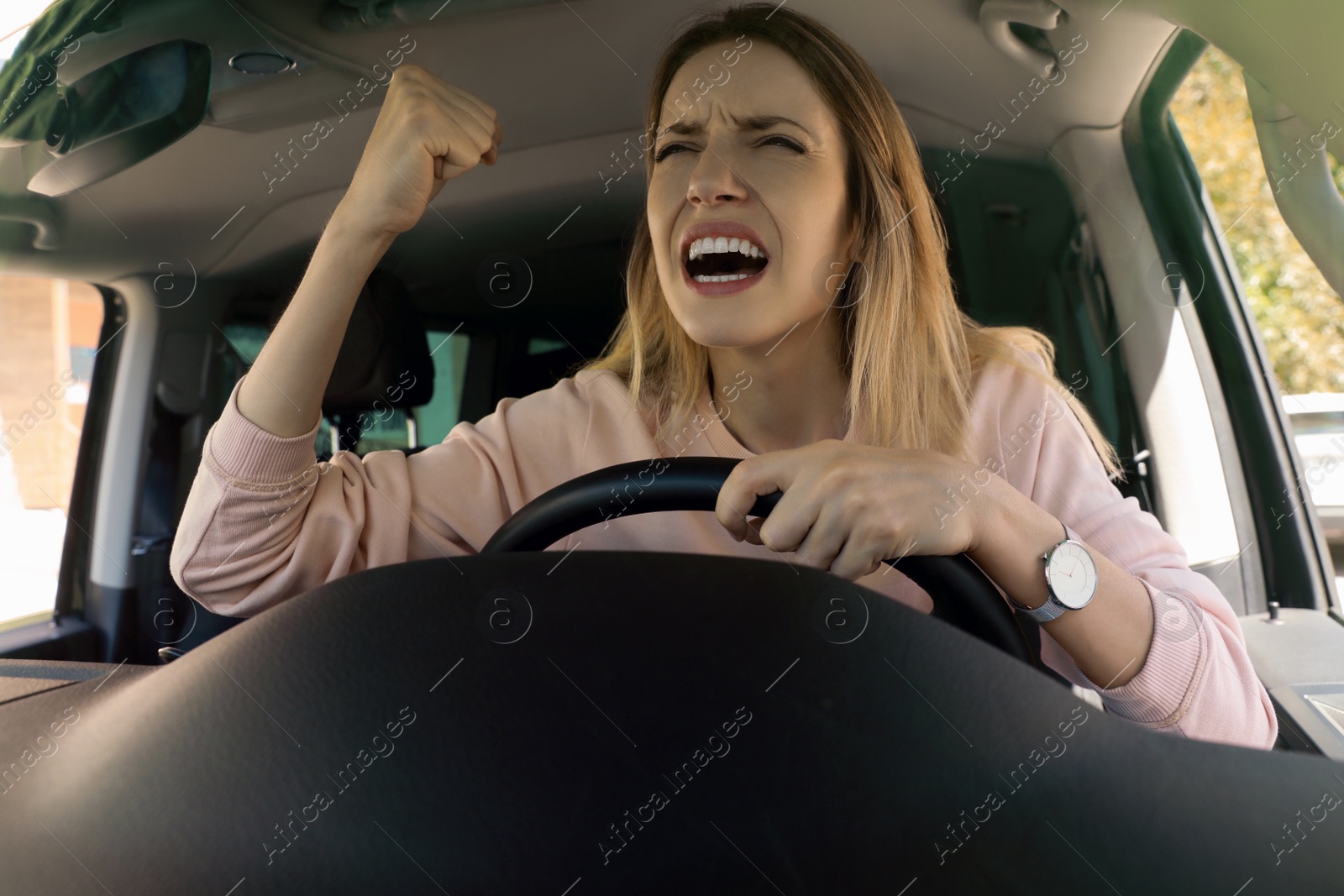 Photo of Stressed angry woman in driver's seat of modern car, view through windshield