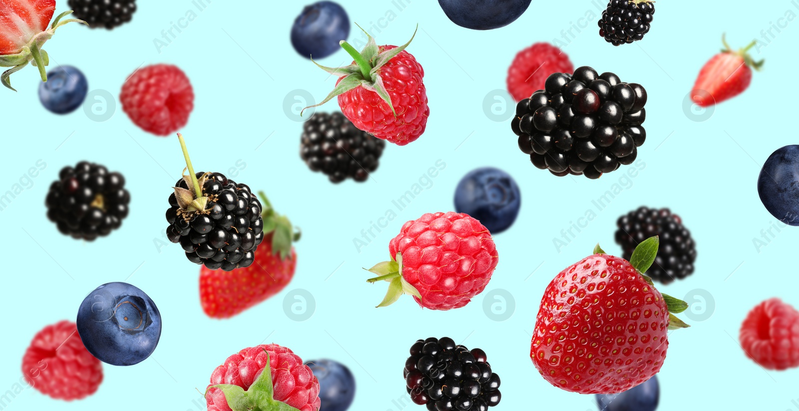 Image of Many different fresh berries falling on light blue background