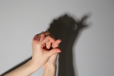 Shadow puppet. Woman making hand gesture like bird on grey background, closeup