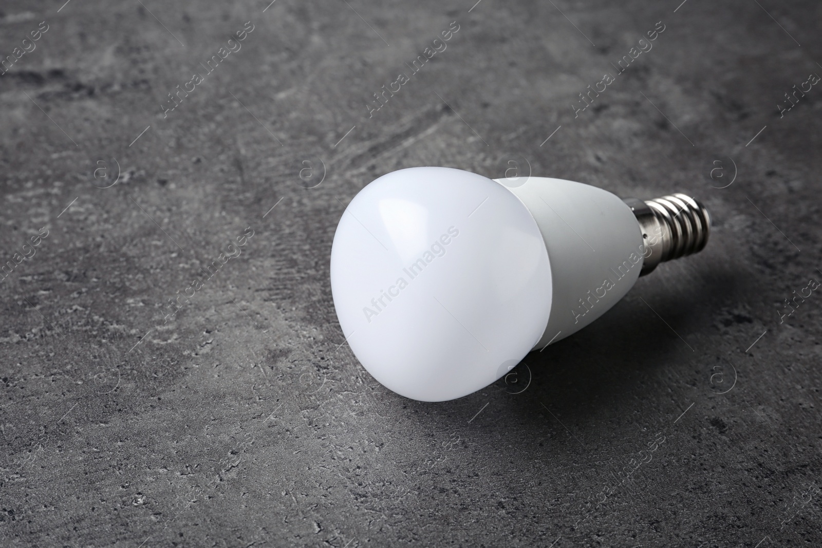 Photo of New modern lamp bulb on grey stone surface
