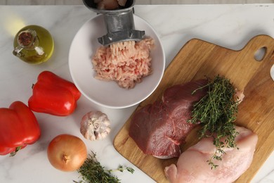 Photo of Metal meat grinder with chicken mince and products on white marble table, flat lay