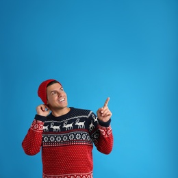 Photo of Happy man in Christmas sweater and hat on blue background