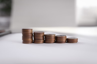 Photo of Stacks of coins on table against blurred background
