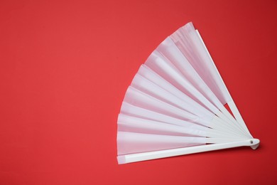 Photo of Stylish white hand fan on red background, top view. Space for text