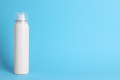 Photo of Bottle of dry shampoo on light blue background, space for text