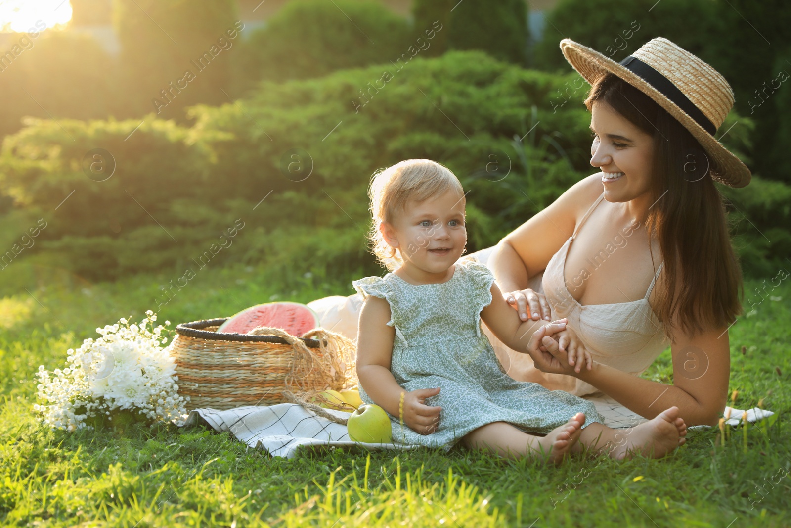 Photo of Mother with her baby daughter having picnic in garden on sunny day