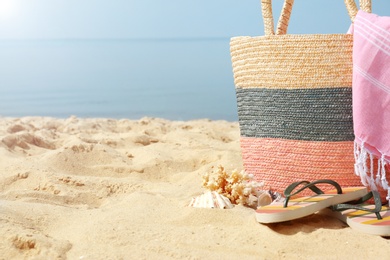 Photo of Bag and flip flops on sand, space for text. Beach accessories