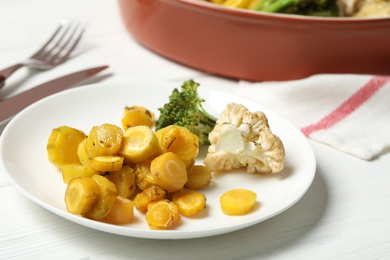 Photo of Baked yellow carrot with broccoli and cauliflowers on white table, closeup
