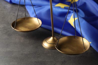 Scales of justice and European Union flag on grey table, closeup