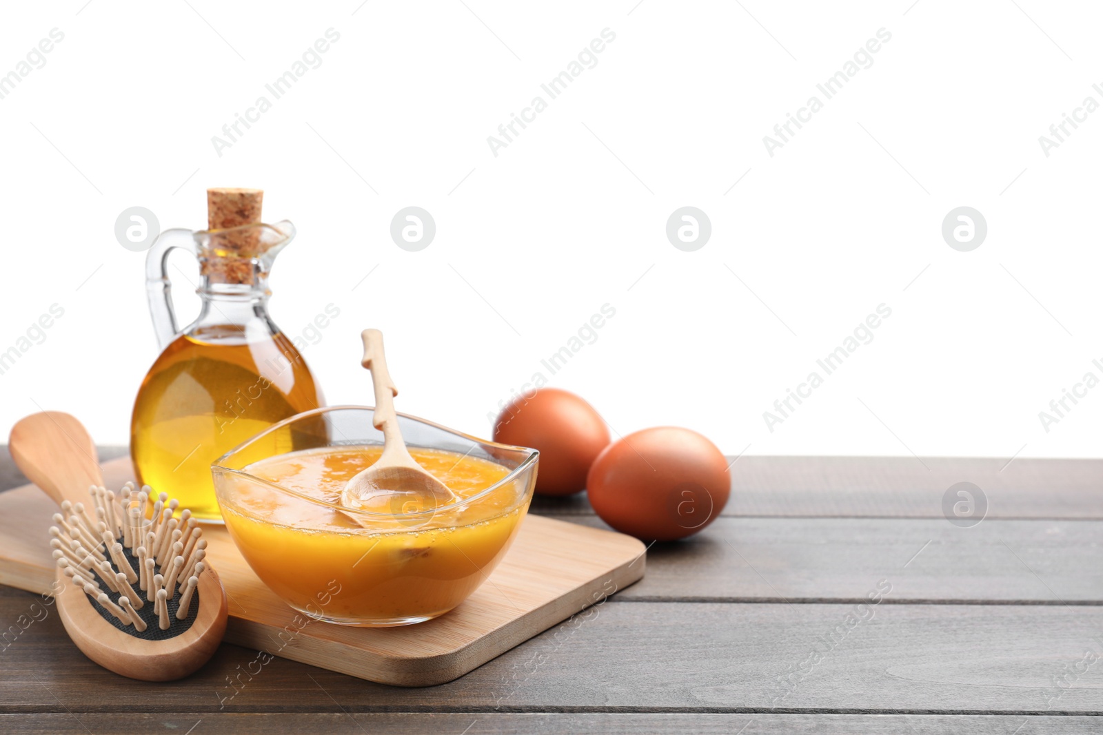 Photo of Homemade hair mask in bowl, fresh ingredients and brush on wooden table against white background. Space for text