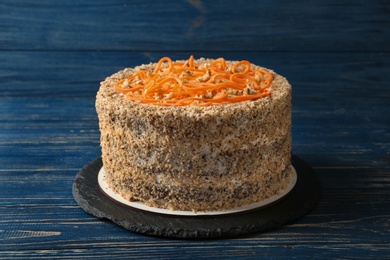 Dish with delicious carrot cake on blue wooden background