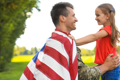 Father in military uniform with American flag and his daughter at sunny park