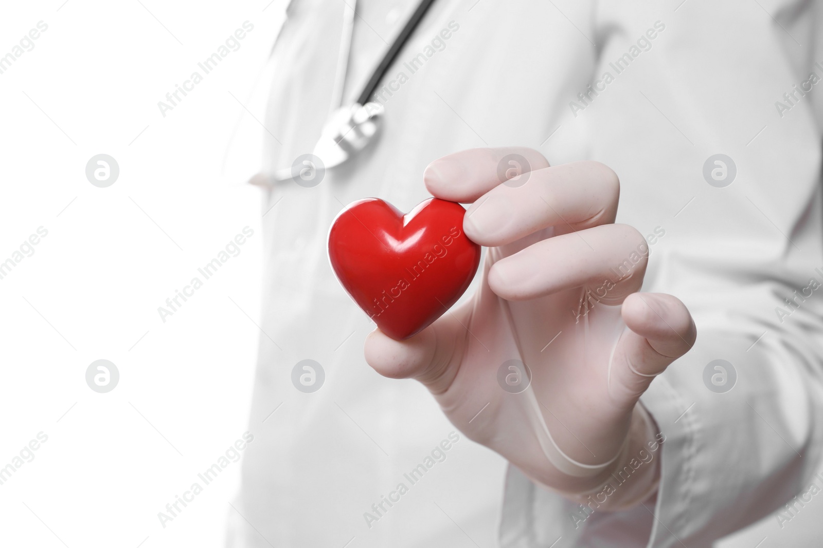 Photo of Doctor in medical glove holding red heart on white background, selective focus